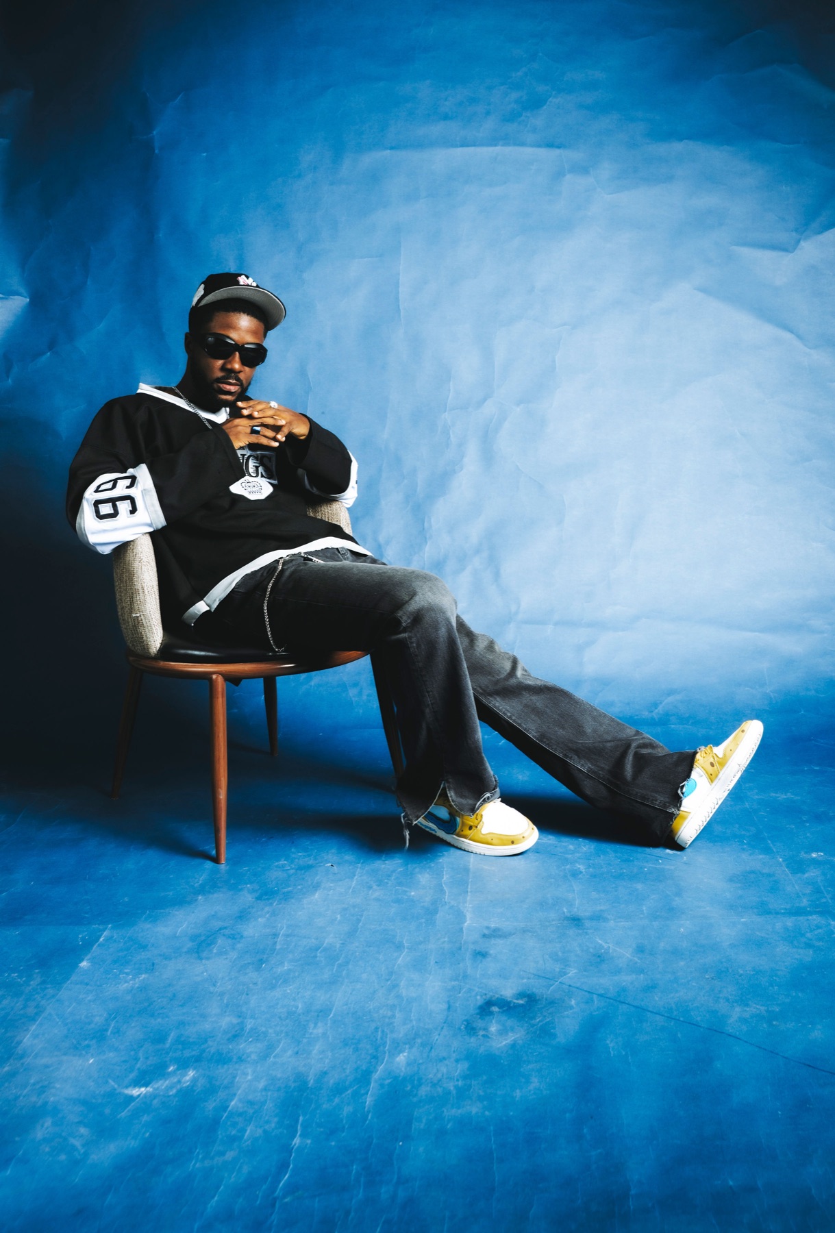Druppy the Kid seated in a chair against a blue studio backdrop